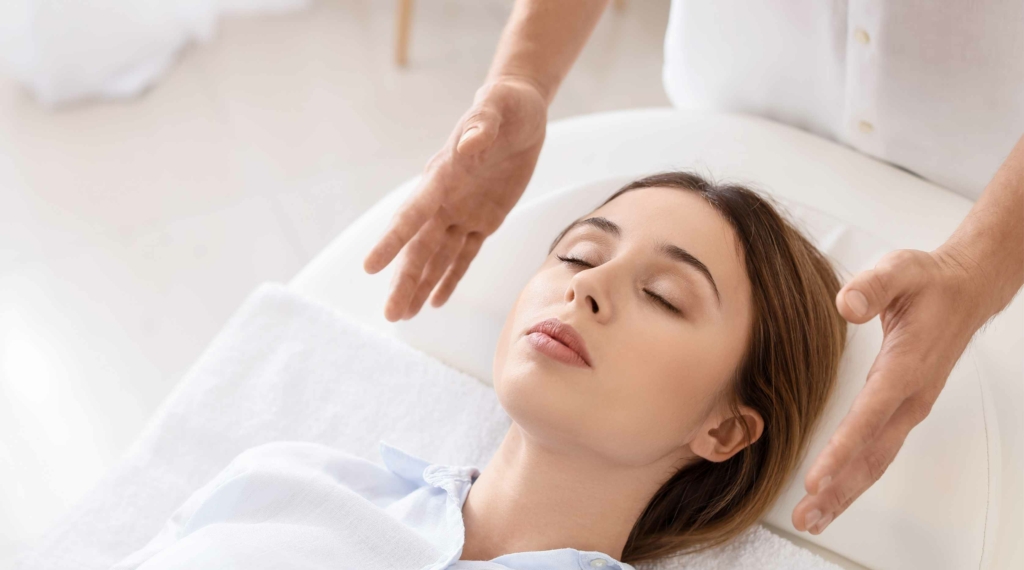 woman lying down with eyes closed receiving Reiki