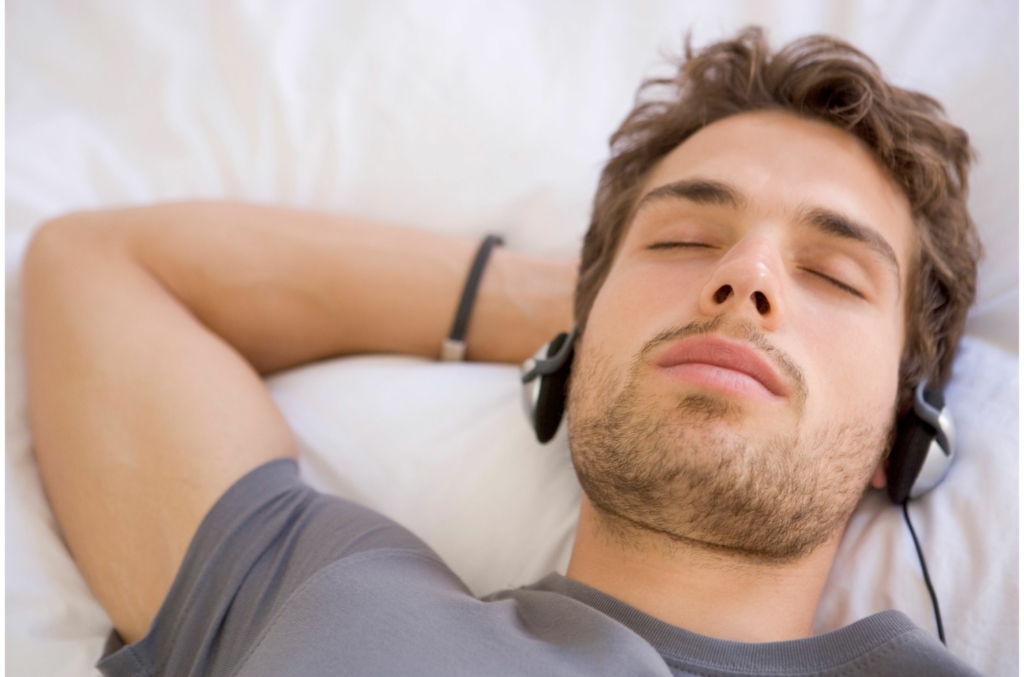 Man laying on couch with eyes closed with headphones on