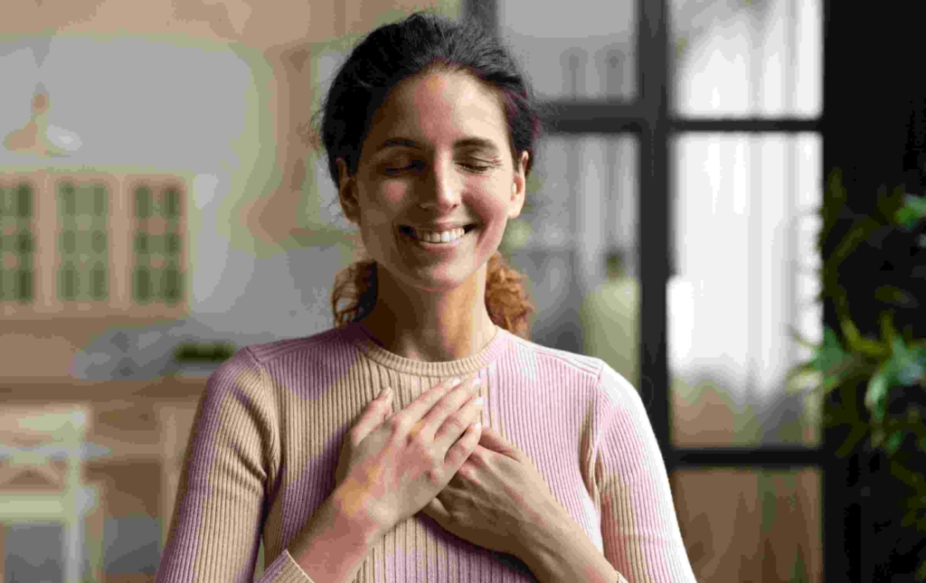woman smiling feeling peaceful with hands on heart after hypnosis
