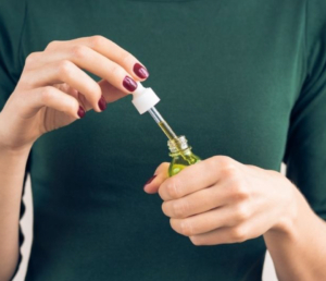 Close up of woman’s arm taking flower essences out of a tincture bottle
