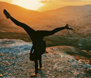 Woman doing a handstand on a mountain top