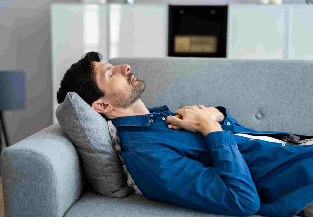 man lying on sofa receiving remote healing distance Reiki session