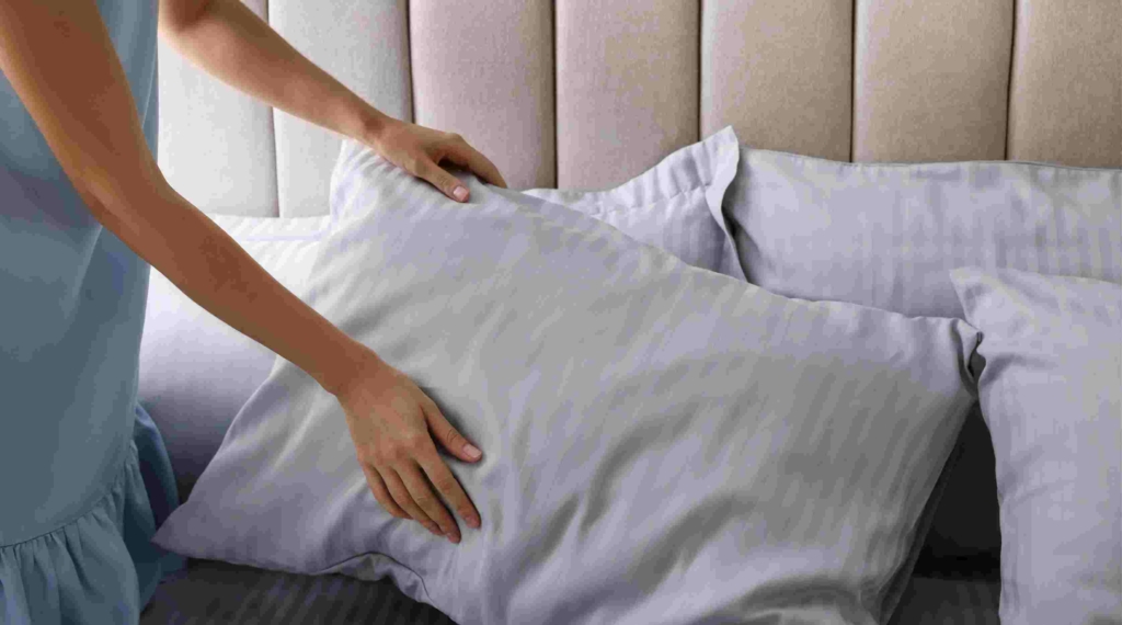 woman's hands fluffing a bed pillow