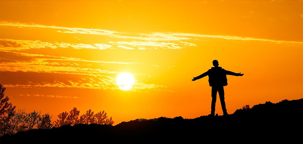 Person with arms outstretched with setting sun in the background