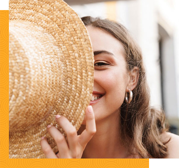 Smiling woman hiding half of her face behind a hat