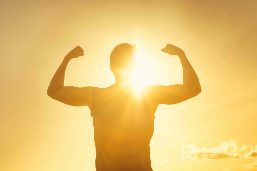 man with sun arms raised making muscles